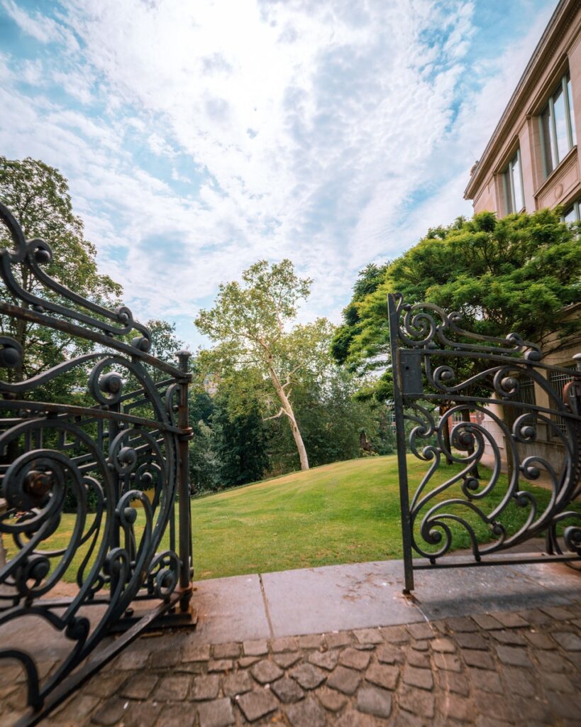 Set of metal gates with one open, at exterior of a large residential building