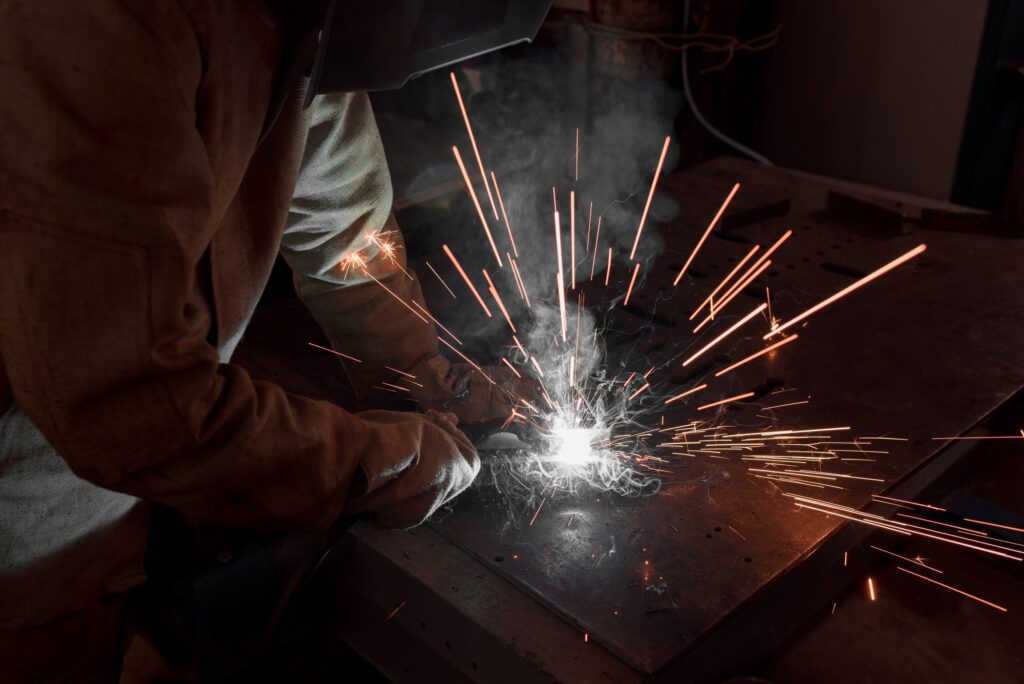 cropped image of welder in protection mask working with metal at factory