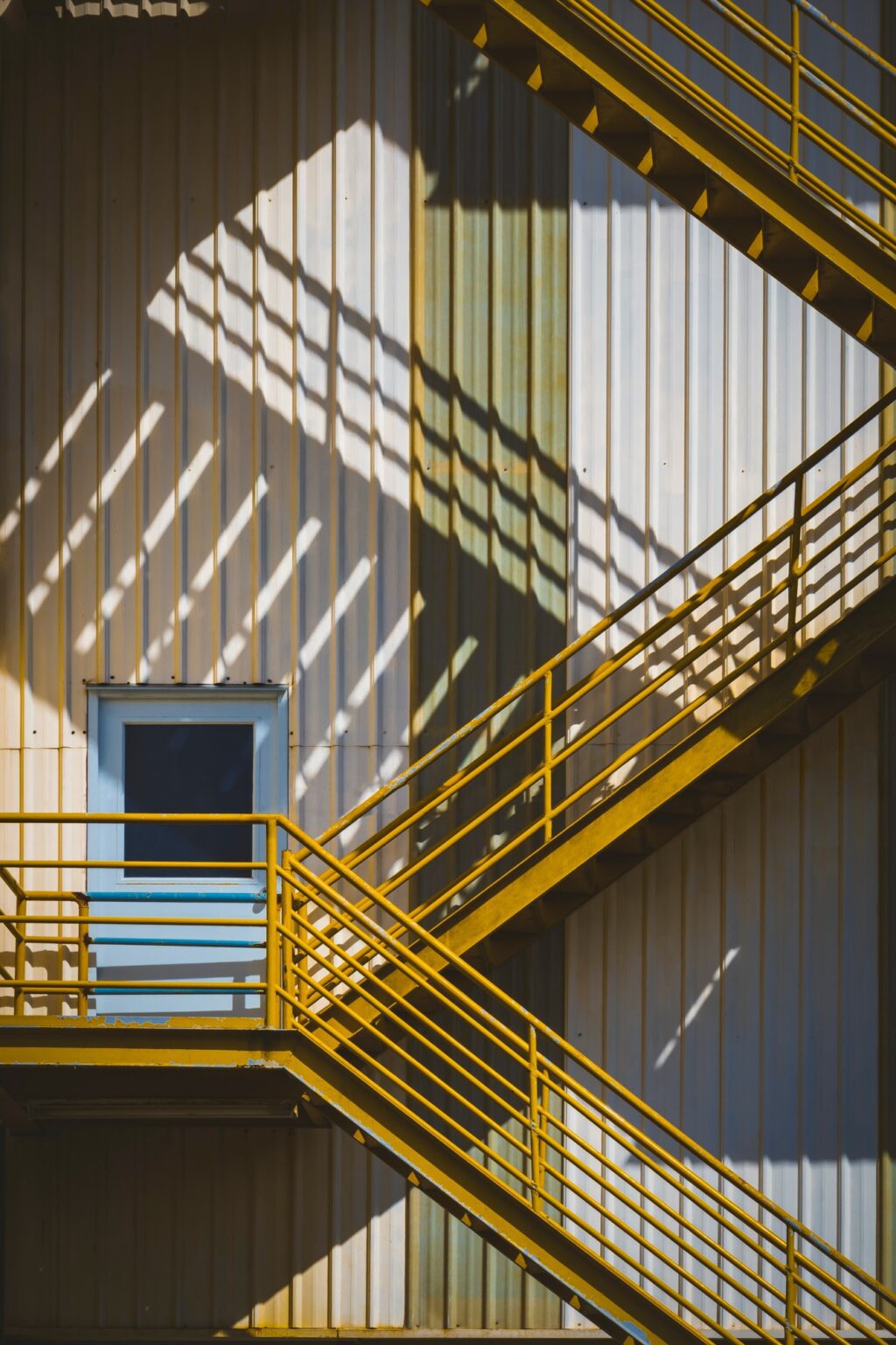 Metal fire escape, yellow coloured, on the side of an industrial building